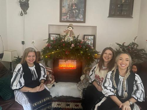 a group of three women sitting in front of a fireplace at Pensiunea Domnescu in Sălişte