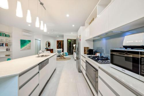 a kitchen with white counters and a stove top oven at Belle Escapes Luxury Beach Edge in Palm Cove