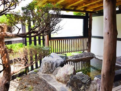 a garden with a pond and rocks and a fence at 伊豆Cocoグランピングリゾート in Ito