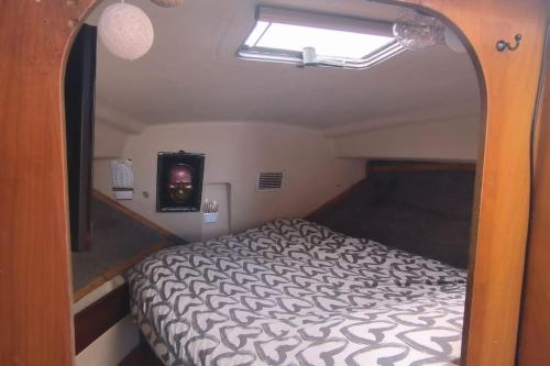 une chambre avec un lit dans une petite pièce dans l'établissement bateau au port, à Ouistreham