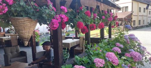 a man sitting on a bench in front of flowers at Pensiunea Domnescu in Sălişte