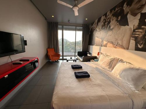 a hotel room with a large bed and a flat screen tv at SinQ Party Hotel - No Male Stags Allowed in Candolim