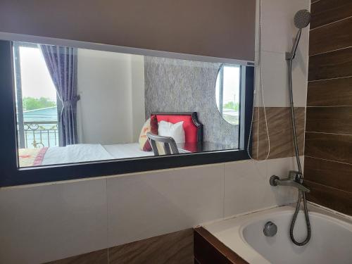 a bathroom with a window with a bed and a tub at RUBY HOTEL Vĩnh Long in Vĩnh Long