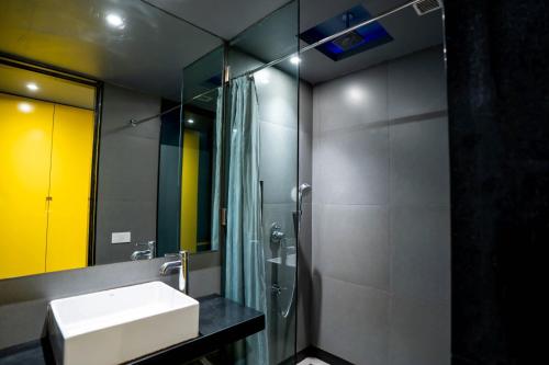 a bathroom with a sink and a shower and a mirror at SinQ Party Hotel - No Male Stags Allowed in Candolim