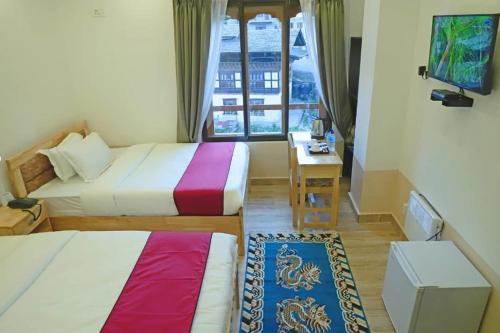 a hotel room with two beds and a desk and a window at The BD Hotel in Thimphu