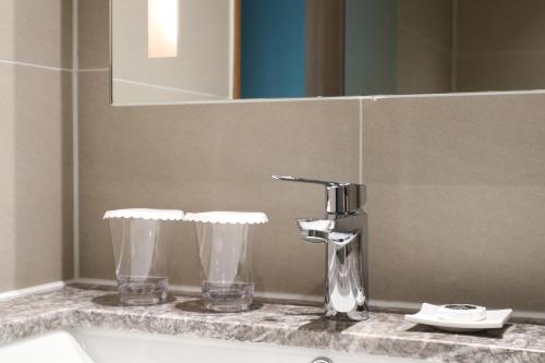 a bathroom sink with a faucet and two glasses at Haenam 126 Hotel in Haenam