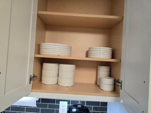 a cupboard full of plates and dishes in a kitchen at Cozy 2 in Regina