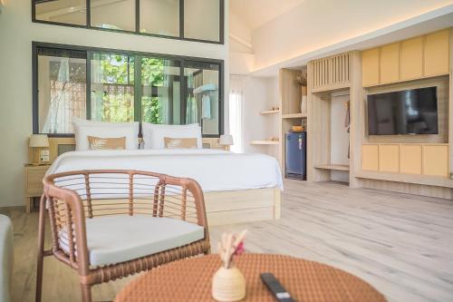 a bedroom with a bed and a chair and a tv at Villa De Leaf River Kaeng Krachan in Phetchaburi