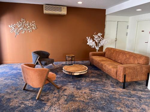 un salon avec un canapé et deux chaises dans l'établissement The Originals City, Hôtel des Arènes, Saintes, à Saintes