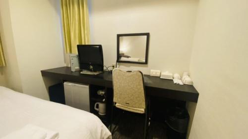 a bedroom with a desk with a computer and a bed at Business Hotel Sunpu in Shizuoka
