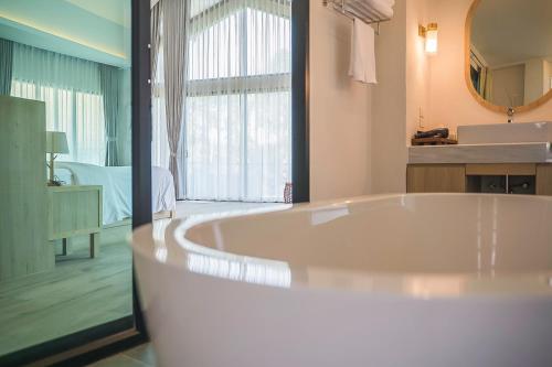 ペッチャブリーにあるVilla De Leaf River Kaeng Krachanの広いバスルーム(バスタブ付)、ベッドルーム1室が備わります。