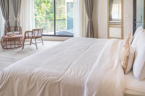 a large white bed in a room with a window at Villa De Leaf River Kaeng Krachan in Phetchaburi