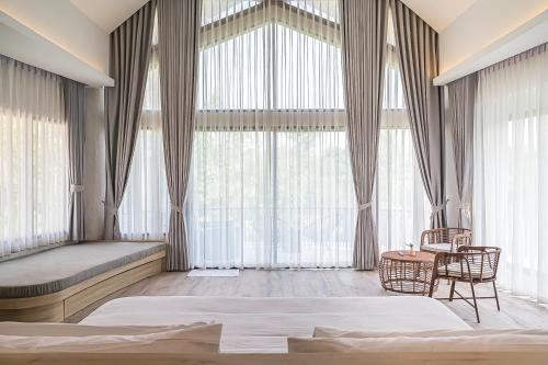 a bedroom with a large window with a bed and a table at Villa De Leaf River Kaeng Krachan in Phetchaburi