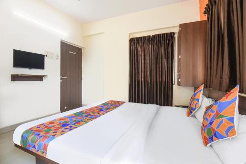 a bedroom with a large white bed with colorful pillows at FabExpress Comfort Executive - Nr Butterfly Park - Hinjawadi in Pune