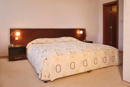 a bedroom with a large bed with a wooden headboard at Хотел Кипарис, Враца in Vratsa