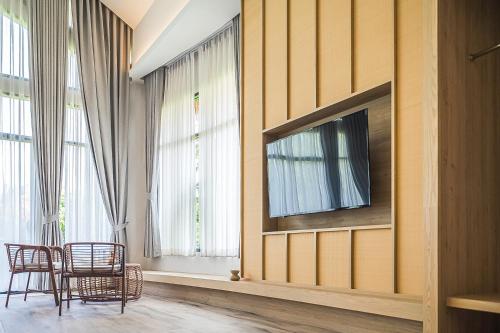 a living room with chairs and a television on a wall at Villa De Leaf River Kaeng Krachan in Phetchaburi