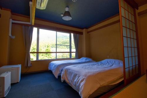 a bedroom with two beds and a large window at Hotel&Resort Yamanouchi Hills in Yamanouchi