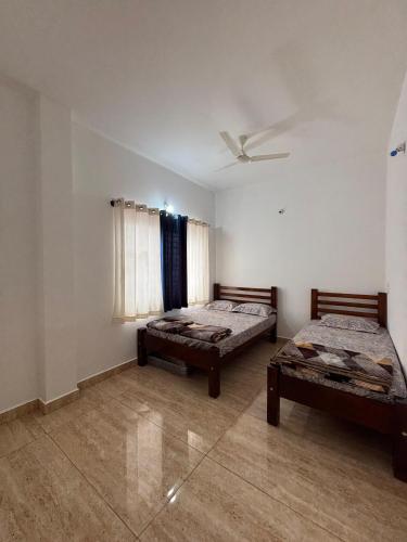 ein Schlafzimmer mit zwei Betten und einem Deckenventilator in der Unterkunft Kamal nivas service apertments in Chikmagalur