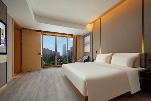 a bedroom with a large white bed and a large window at Atour Hotel Suzhou Wuzhong Taihu New Town in Suzhou