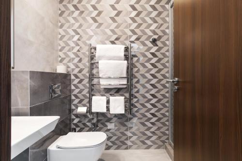 a bathroom with a toilet and a sink and towels at AN Hotel self check-in in Šiauliai