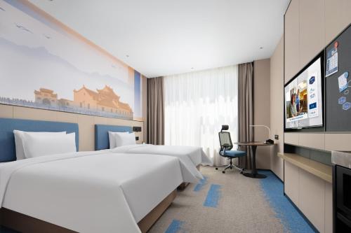 a hotel room with two beds and a tv at Hilton Garden Inn Jiujiang Changhong Avenue in Jiujiang