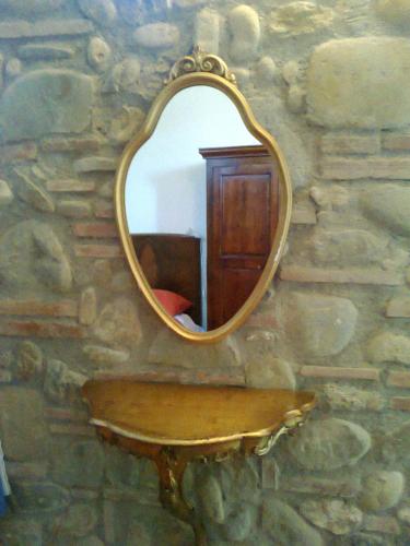 a mirror on a stone wall with a wooden table at Relais Del Lago in Capannori