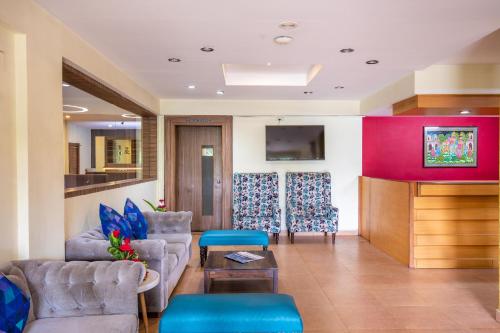 a living room with two couches and a tv at Vinayaga Inn by Poppys, Ooty in Ooty