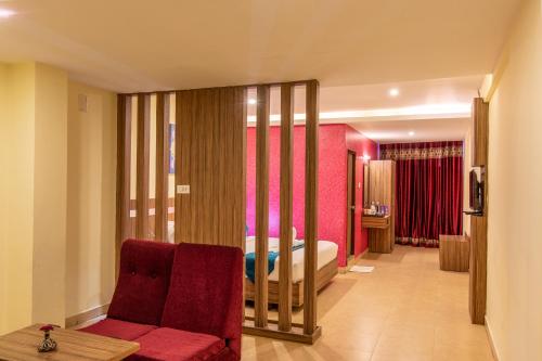 a hotel room with a bed and a red couch at Vinayaga Inn by Poppys, Ooty in Ooty