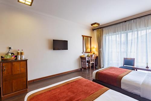 a hotel room with two beds and a television at Atithi Resort & Spa in Pokhara