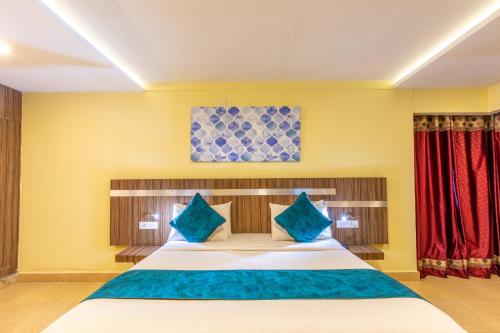 a bedroom with a large bed with blue pillows at Vinayaga Inn by Poppys, Ooty in Ooty