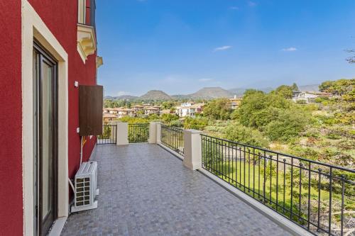 a balcony of a red building with a view at Badimà - Villa con piscina in Aci SantʼAntonio