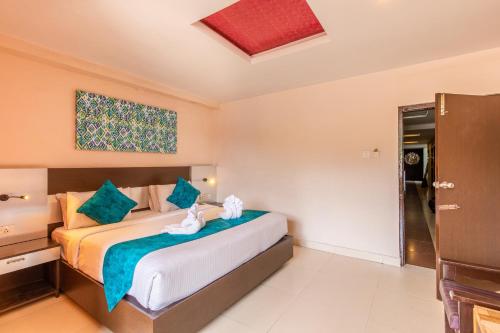 a bedroom with a large bed with blue pillows at Vinayaga Inn by Poppys, Ooty in Ooty