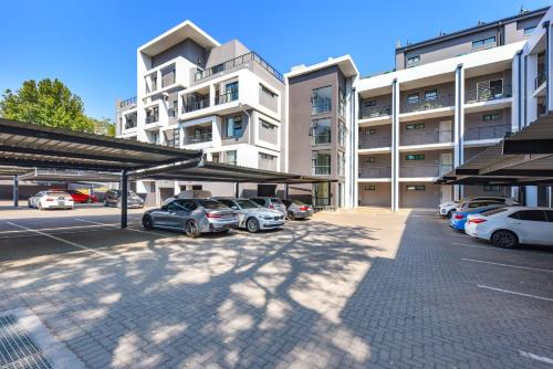 a parking lot with cars parked in front of a building at The Odyssey Lifestyle Complex Morningside - 2 BR in Johannesburg