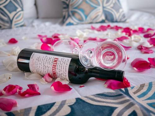 a bottle of wine laying on a bed with roses at Casa Antares24, Departamento de confort y descanso in Guanajuato