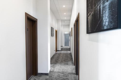 a corridor with white walls and a hallway with black doors at AN Hotel self check-in in Šiauliai