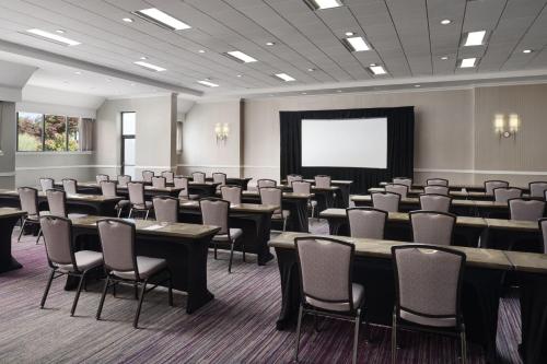 a conference room with tables and chairs and a screen at Hanover Marriott in Whippany