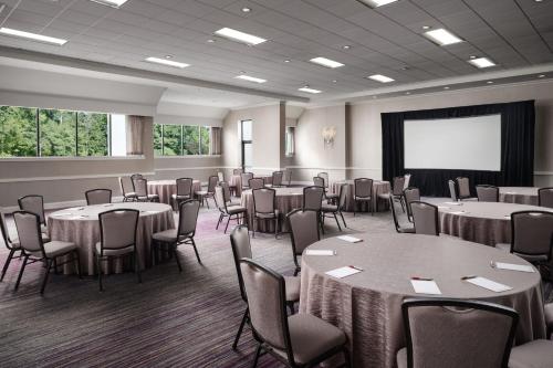 a conference room with tables and chairs and a screen at Hanover Marriott in Whippany