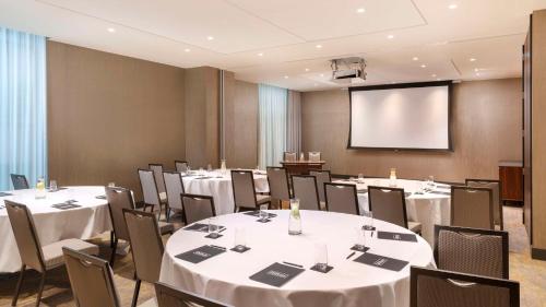 a conference room with tables and chairs and a screen at Hilton Woking in Woking