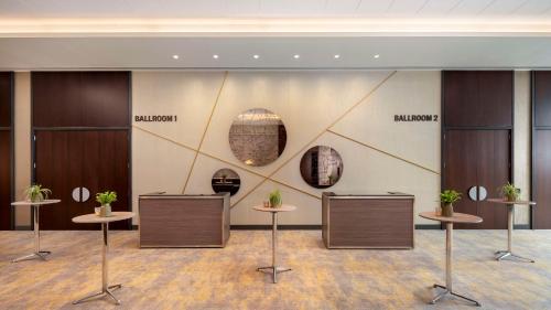 a lobby with tables and potted plants on a wall at Hilton Woking in Woking