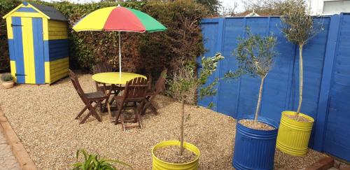 a patio with a table and chairs and an umbrella at Rainbow on Sea Frinton-on-Sea in Kirby Cross