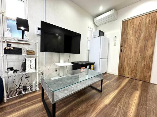 a room with a glass table with a tv on the wall at LAINA Kyobashi in Osaka
