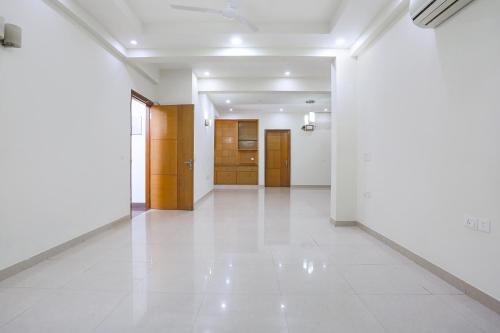 an empty hallway with white floors and wooden doors at FabHotel New Journey Hospitality Near MG Road & Sikanderpur Metro in Gurgaon