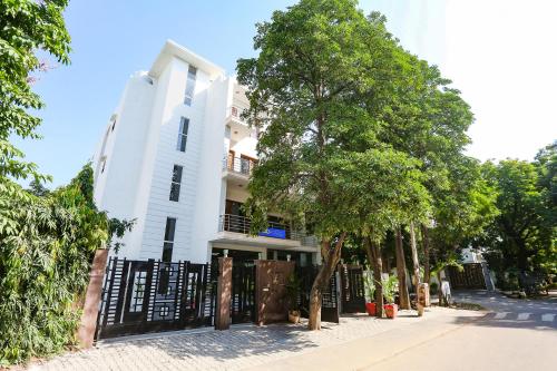 a white building with a black fence and trees at FabHotel New Journey Hospitality Near MG Road & Sikanderpur Metro in Gurgaon