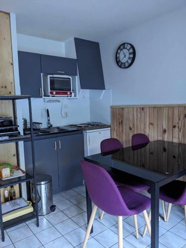 une cuisine avec des chaises violettes, une table et une horloge dans l'établissement 2 pieces Morzine, à Morzine