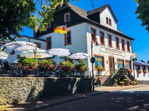 a building with tables and umbrellas in front of it at Ferienwohnung Ankerplatz in Schalkenmehren