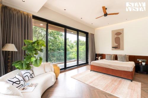 un soggiorno con un letto e un divano di StayVista at Sol & Sands with Mountain View and Pool a Alibag