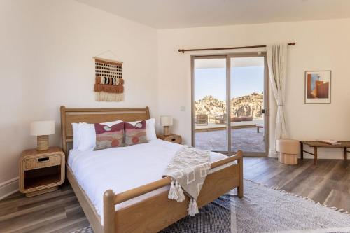 a bedroom with a bed and a large window at Casa Blanca by Fieldtrip Boulder Estate with Hot Tub Soaking Pool Outdoor Shower in Yucca Valley