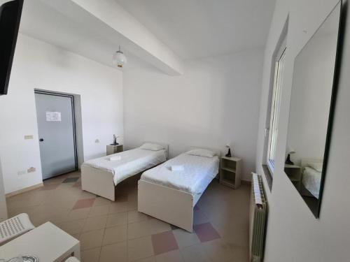 a white room with two beds and a mirror at Pensiunea Eurosan Slănic-Moldova in Slănic-Moldova