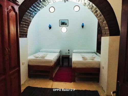 two beds in a room with an archway at palm shadow resort in Tunis