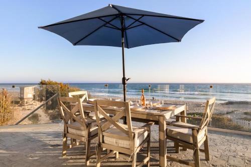 a table with an umbrella on the beach at Malibu Dunes by Fieldtrip Expansive Hamptons-Style Estate w Private Beach Backyard in Malibu